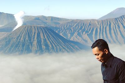 Mid adult man standing by mountains against sky