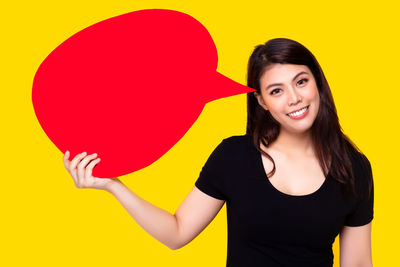 Portrait of a smiling young woman against yellow background