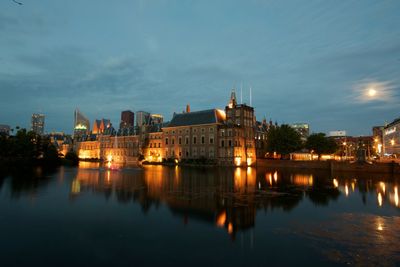 Reflection of illuminated buildings in city on river during dusk