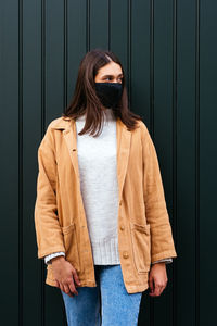 Portrait of woman standing against wall