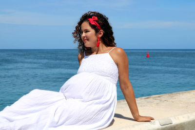 Beautiful young woman at beach against sky