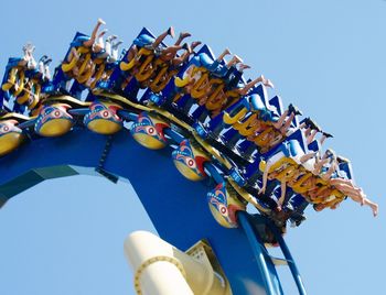 Low angle view of people on roller coaster ride against sky