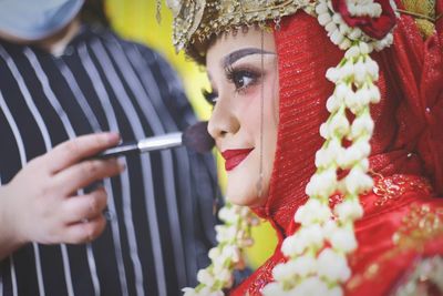 Close-up of beautician applying make-up to bride