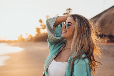 Young woman wearing sunglasses standing against sky