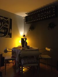 Rear view of man standing on table against illuminated wall