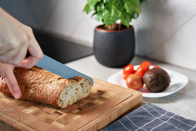 Woman cutting loaf of bread with large knife