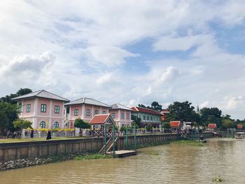 Houses by river and buildings against sky