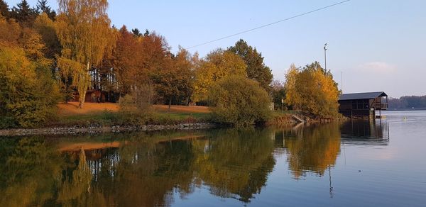 Scenic view of lake by trees and buildings against sky