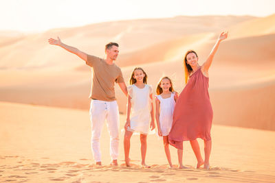 Full length of parents with daughters standing at desert