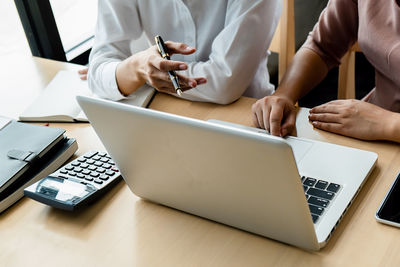 Midsection of man using mobile phone on table