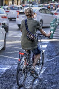 Rear view of man riding bicycle on city street