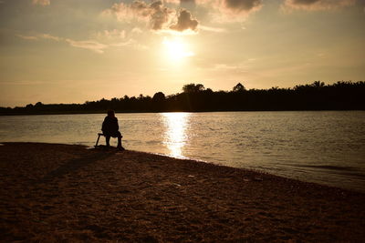 Silhouette man on beach against sky during sunset