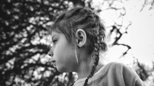 Close-up of young girl against tree