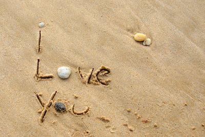 High angle view of i love you text on sand at beach