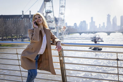 Portrait of young woman sitting on railing