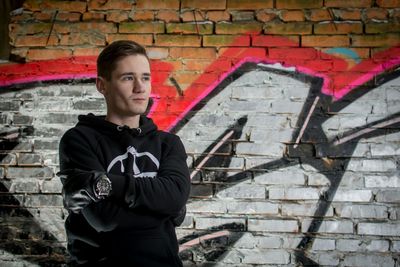 Portrait of young man standing on brick wall