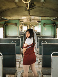 Portrait of woman standing on seat in train