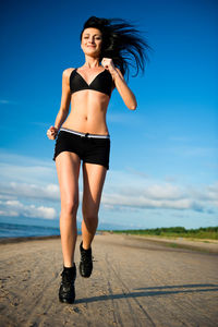 Portrait of smiling young woman standing by sea against sky