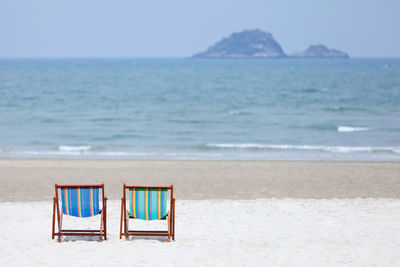 Chair on beach against sky