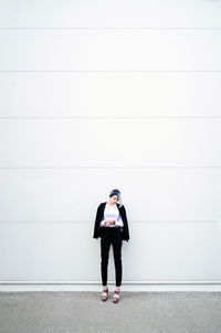Full length of young man standing against wall