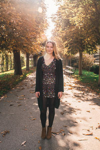 Portrait of smiling young woman standing in park during autumn
