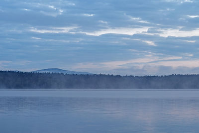 Scenic view of lake by trees against sky