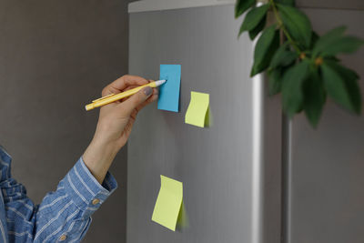 Midsection of man holding paper against wall