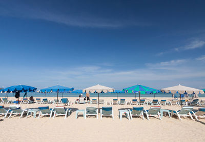 Chairs on beach against blue sky