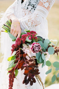 Midsection of bride holding bouquet