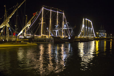 Illuminated bridge over river against sky at night