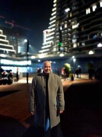 Portrait of young man standing in city at night