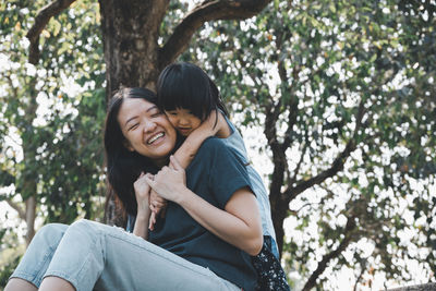 Happy mother and daughter against trees