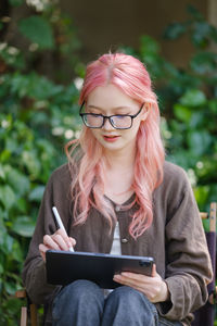 Young woman using mobile phone while sitting outdoors