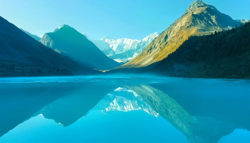 Scenic view of lake by mountains against blue sky