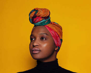 Close-up portrait of a serious young woman against yellow background