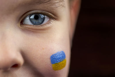 Child's eye and ukrainian flag is drawn on his cheek