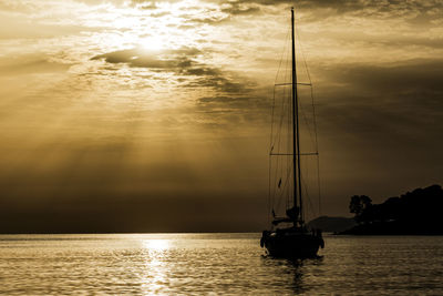 Sailboat in sea against sky during sunset