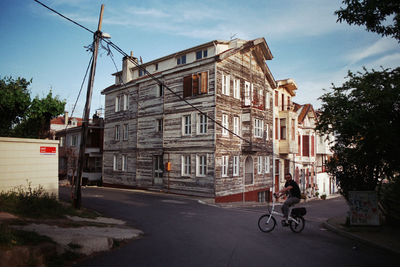 Man bicycling on road along built structures