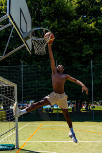 Young african american basketball player athlete in action jumping on artificial turf playing field