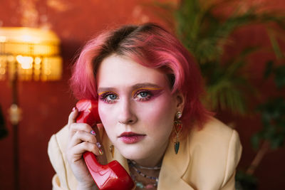 Young fashion woman posing with retro phone, bright make up and colored hair