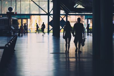 Silhouette couple holding hands while walking at railroad station