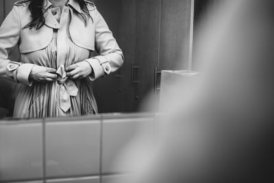 Midsection of woman dressing up reflecting on mirror