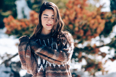 Young woman with eyes closed standing outdoors during winter