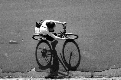 Woman riding bicycle on street, from above 