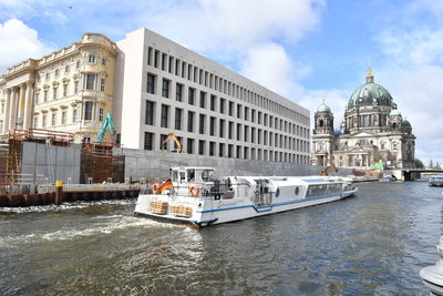 Boats in canal by buildings against sky in city