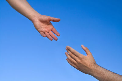 Low angle view of hand against clear blue sky