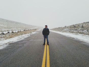 Full length of man standing on road against clear sky