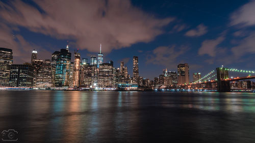 Illuminated modern buildings in city against sky at night