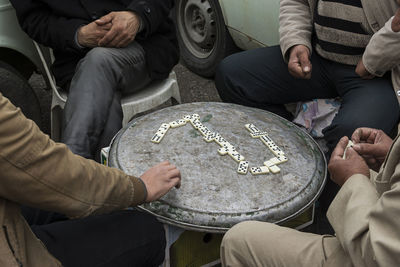 Midsection of men playing with dominoes on metal container