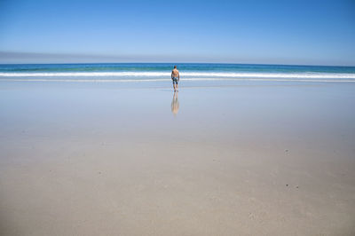 Man standing on beach against clear sky